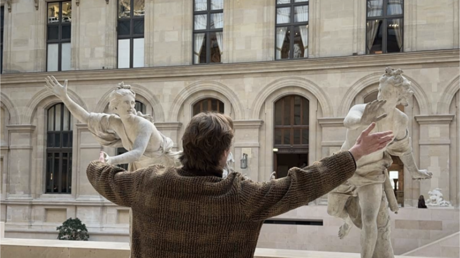 Gunner posing with outstretched arms among museum sculptures.
