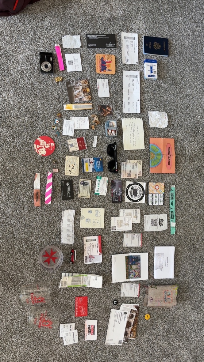 Tickets, postcards, and travel keepsakes arranged on a carpet.